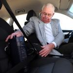 Ein Mann sitzt im Auto und sichert den Sprint mit dem Gurt auf dem Beifahrersitz.