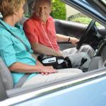 Ein Ehepaar sitzt im Auto. Zwischen beiden steht der Inogen One G5. - Inogen One G5