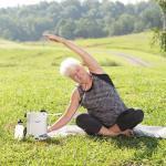 Eine Frau sitzt auf einer Wiese und macht Yoga. Neben ihr steht der FreeStyle Comfort.
