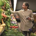 Eine Dame geht im Supermarkt einkaufen, der SimplyGo mini steht in ihrem Einkaufswagen. - SimplyGo mini